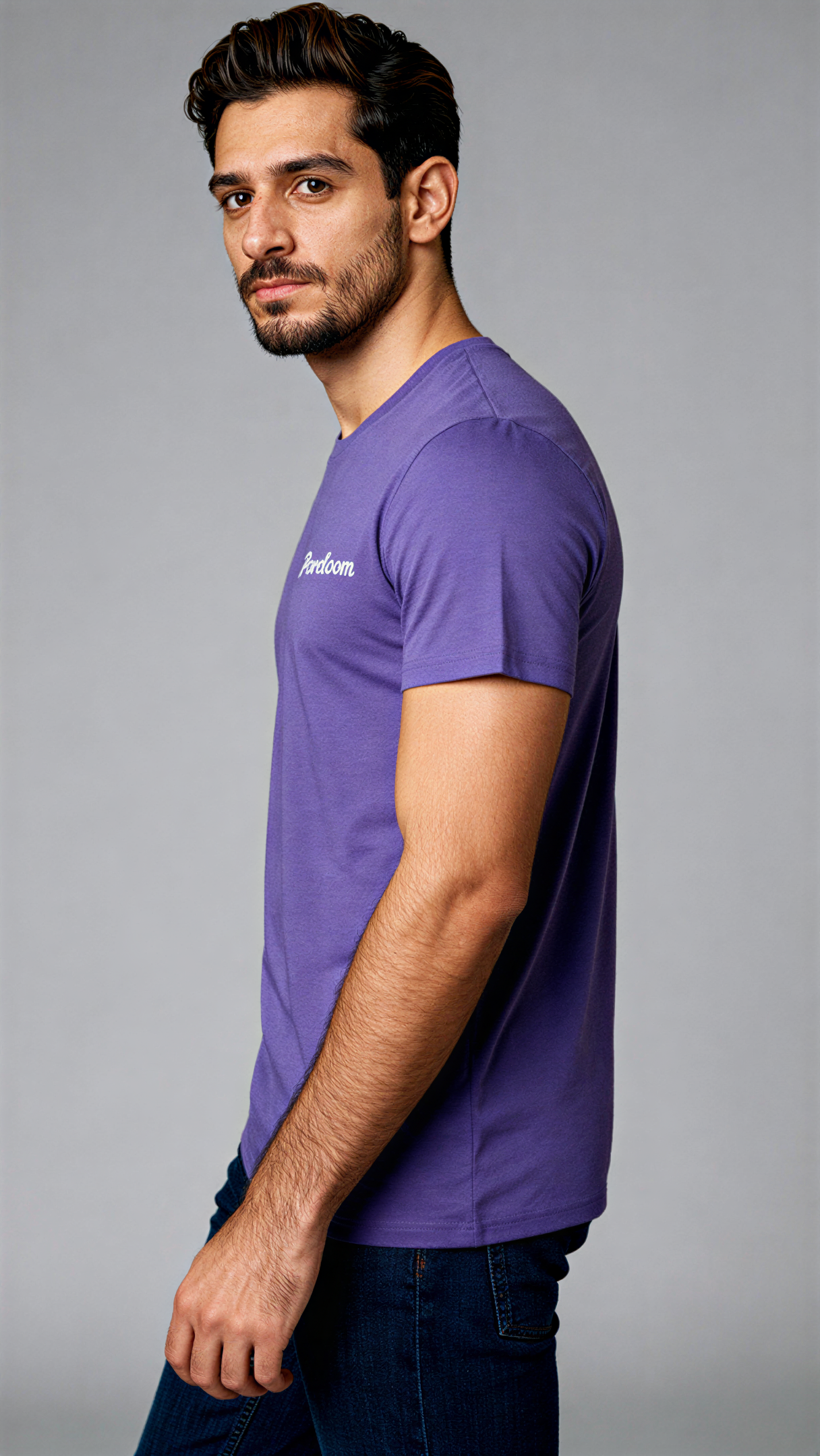 במבט צדדי, גבר לובש חולצת כותנה אורגנית סגולה עם לוגו לבן "Pureloom" בצד שמאל של החזה מבית פיורלום.